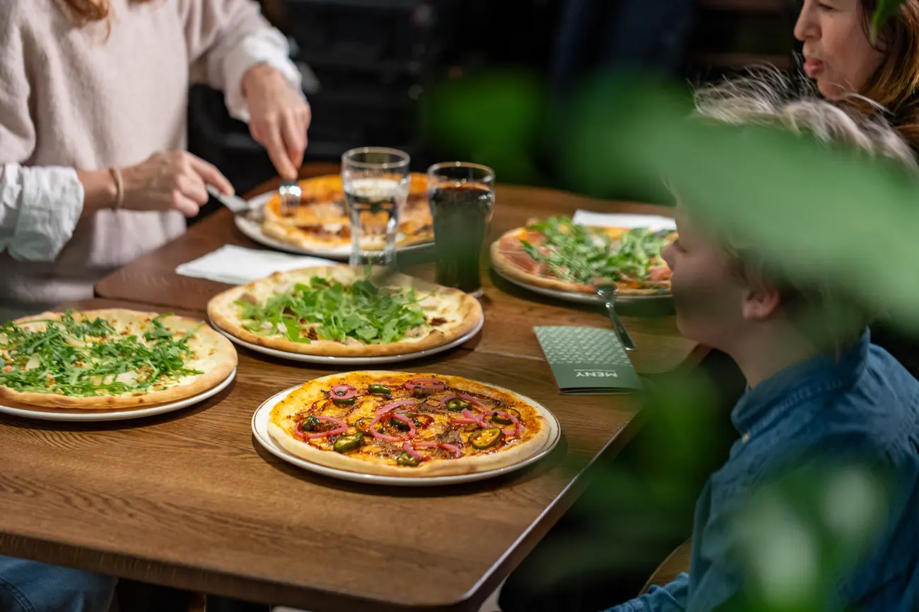Pizza och sällskap runt ett bord på Just In Time