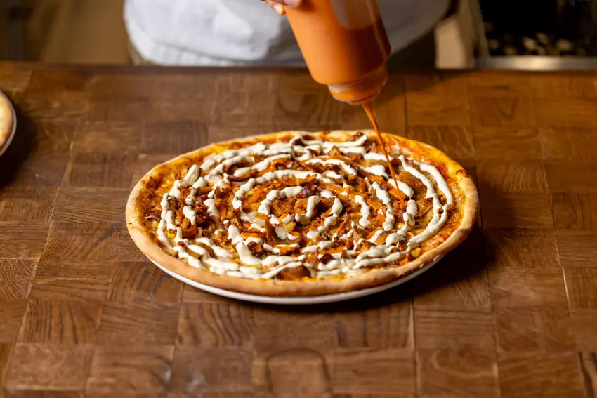 Sås ringlas över en nybakad kebabpizza